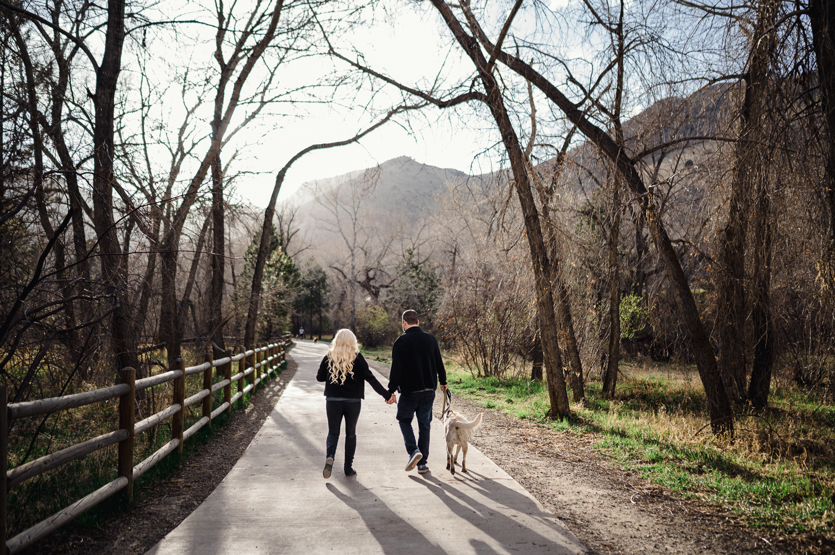 A couple walking hand in hand with their dog next to Clear Creek in Golden, Colorado