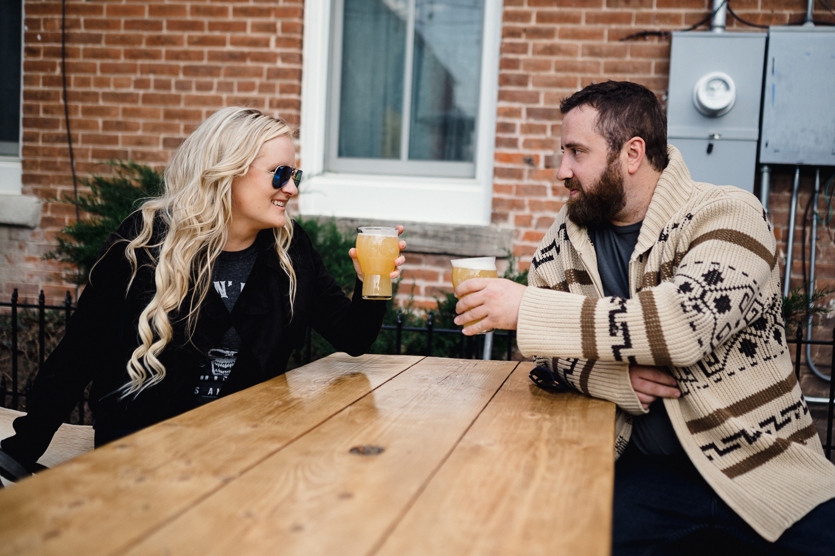 A couple drinking at a brewery for engagement photos next to Clear Creek in Golden, Colorado