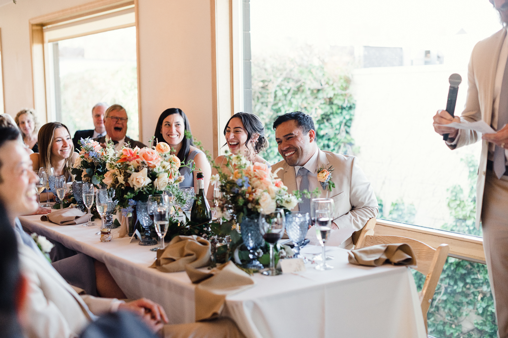 A group of family and friends laughing and toasting in celebration of the couple's boulder colorado wedding, radiating joy and love at the reception.